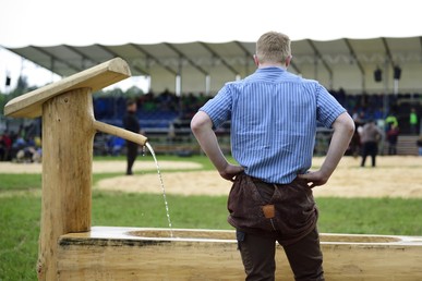 Ein junger Schwinger steht mit dem Rücken zur Kamera. Er schaut sich einen Wettkampf an.